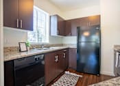 Thumbnail 18 of 72 - A kitchen with a black fridge and wooden cabinets at Riverplace Apartment Homes, Independence