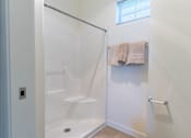 Thumbnail 32 of 72 - A white bathroom with a glass shower door and towels hanging on a rack at Riverplace Apartment Homes, Independence