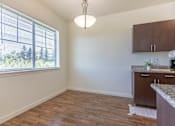 Thumbnail 36 of 72 - A kitchen area with a window and wooden flooring at Riverplace Apartment Homes, Independence, OR, 97351