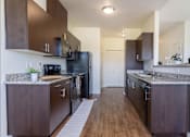 Thumbnail 37 of 72 - A kitchen with dark wood cabinets and a granite countertop at Riverplace Apartment Homes, Independence, Oregon