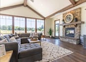 Thumbnail 48 of 72 - A living room with a grey couch and a stone fireplace at Riverplace Apartment Homes, Independence, Oregon