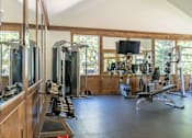 Thumbnail 52 of 72 - A spacious gym with a variety of equipment including treadmills, weights, and a television at Riverplace Apartment Homes, Oregon