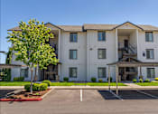 Thumbnail 70 of 72 - A large white apartment building with a tree in front at Riverplace Apartment Homes, Independence, Oregon