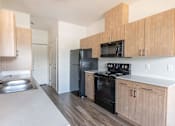 Thumbnail 11 of 28 - A kitchen with wooden cabinets and black appliances at Silverplace Apartment Homes, Silverton, OR