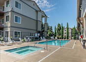 Thumbnail 14 of 28 - A swimming pool surrounded by lounge chairs and apartment buildings at Silverplace Apartment Homes, Oregon, 97381