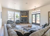 Thumbnail 20 of 28 - A living room with a stone fireplace and a grey couch at Silverplace Apartment Homes, Silverton, Oregon