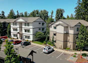 Thumbnail 24 of 28 - A white and beige apartment complex with a parking lot in front at Silverplace Apartment Homes, Silverton, OR, 97381