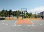 Thumbnail 28 of 28 - A basketball court with a hoop and a grey floor with orange area in the middle at Silverplace Apartment Homes, Silverton, 97381