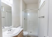Thumbnail 8 of 28 - A white bathroom with a toilet, sink, and shower at Silverplace Apartment Homes, Silverton