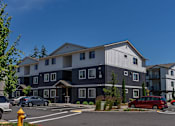 Thumbnail 11 of 22 - A building with a parking lot in front of it at St Helens Place Apartment Homes, St Helens
