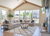 Thumbnail 16 of 22 - A living room with a couch, a coffee table, and a TV at St Helens Place Apartment Homes, Oregon