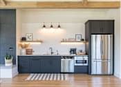Thumbnail 17 of 22 - A kitchen with a black fridge and a white sink at St Helens Place Apartment Homes, St Helens, OR