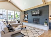Thumbnail 18 of 22 - A modern living room with a grey couch, a black and white rug, and a fireplace at St Helens Place Apartment Homes, Oregon, 97051