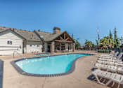 Thumbnail 1 of 46 - A pool with chairs around it and a building in the background at Stoneplace Apartment Homes, Molalla, OR, 97038