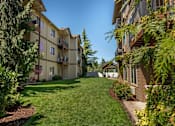 Thumbnail 12 of 46 - A sunny day at a grassy courtyard surrounded by apartment buildings at Stoneplace Apartment Homes, Oregon