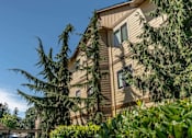 Thumbnail 14 of 46 - A building with a brown wooden exterior and a tree in front of it at Stoneplace Apartment Homes, Molalla, OR, 97038