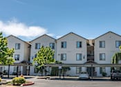 Thumbnail 16 of 46 - A large white building with a parking lot in front at Stoneplace Apartment Homes, Molalla, OR, 97038