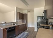 Thumbnail 21 of 46 - A modern kitchen with dark wood cabinets and stainless steel appliances at Stoneplace Apartment Homes, Oregon