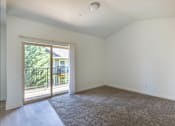 Thumbnail 28 of 46 - A room with a carpeted floor and a sliding glass door leading to a balcony at Stoneplace Apartment Homes, Molalla