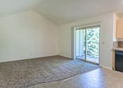 Thumbnail 29 of 46 - A room with a carpeted floor and a sliding glass door leading to a balcony at Stoneplace Apartment Homes, Molalla, OR