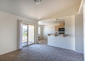 Thumbnail 38 of 46 - A spacious living room with a grey carpet and a sliding glass door leading to a balcony at Stoneplace Apartment Homes, Molalla, OR, 97038