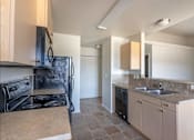 Thumbnail 40 of 46 - A kitchen with a black stove top oven and a black refrigerator at Stoneplace Apartment Homes, Molalla, 97038