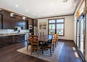 Thumbnail 5 of 46 - A kitchen with dark wood cabinets and a dining table with chairs at Stoneplace Apartment Homes, Molalla