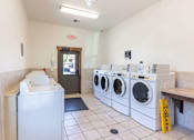 Thumbnail 7 of 46 - A laundromat with washers and dryers and an exit sign at Stoneplace Apartment Homes, Molalla