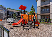 Thumbnail 10 of 12 - A playground with a red slide and orange structure at Timberridge Place Apartment Homes, Albany, Oregon