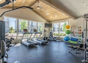 Thumbnail 3 of 12 - A spacious gym with a variety of exercise equipment and a large window overlooking the outdoors at Timberridge Place Apartment Homes, Albany, OR, 97322