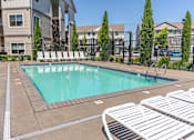 Thumbnail 7 of 12 - A swimming pool surrounded by white lounge chairs at Timberridge Place Apartment Homes, Oregon