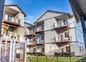 Thumbnail 11 of 49 - Apartment complex with a playground in front at Woodburn Place Apartment Homes, Woodburn, OR
