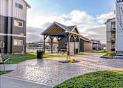 Thumbnail 12 of 49 - A pavement with a circular pattern is in the foreground of a residential area at Woodburn Place Apartment Homes, Woodburn