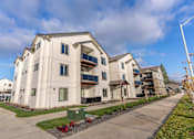 Thumbnail 16 of 49 - Apartment complex with a green dumpster in front at Woodburn Place Apartment Homes, Oregon
