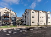 Thumbnail 18 of 49 - Apartment buildings with a parking lot in front at Woodburn Place Apartment Homes, Oregon