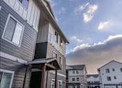 Thumbnail 4 of 49 - A row of houses with a cloudy sky above them at Woodburn Place Apartment Homes, Woodburn