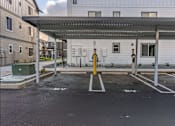 Thumbnail 49 of 49 - A parking lot with a canopy and a few parking spaces at Woodburn Place Apartment Homes, Woodburn, OR, 97071