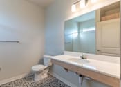 Thumbnail 43 of 49 - A bathroom with a toilet, sink, and mirror at Woodburn Place Apartment Homes, Woodburn, 97071