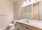Thumbnail 48 of 49 - A white toilet sits in a bathroom next to a sink at Woodburn Place Apartment Homes, Oregon, 97071