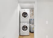 Thumbnail 23 of 24 - A white washing machine and dryer in a small laundry room.