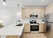 Thumbnail 22 of 24 - A modern kitchen with a white countertop and stainless steel appliances.