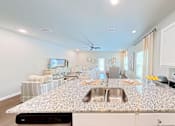 Thumbnail 2 of 13 - A kitchen with a granite countertop and a fan on the ceiling.