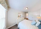 Thumbnail 3 of 13 - A bedroom with a bed, dresser, and mirror.