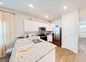 Thumbnail 4 of 13 - A kitchen with granite countertops and white cabinets.