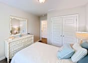 Thumbnail 7 of 13 - A white bedroom with a bed, dresser, and mirror.