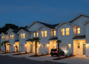 Thumbnail 12 of 13 - A row of houses with lights on and a car parked in front.
