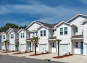 Thumbnail 2 of 9 - A row of white houses with blue doors and windows.