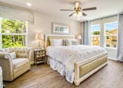 Thumbnail 1 of 9 - A bedroom with a large bed, a chair, and a ceiling fan.