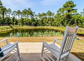 Thumbnail 5 of 9 - Two chairs are placed on a concrete slab with a pond and trees in the background.