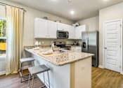 Thumbnail 6 of 9 - A kitchen with a granite countertop and stainless steel appliances.